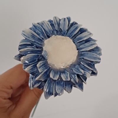 Vela branca formato flor com pétalas azuis nas mãos