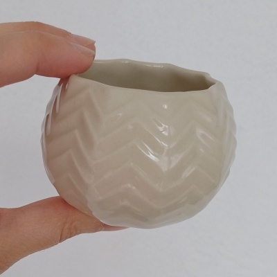 Vaso pequeno redondo de cerâmica bege com padrão em ziguezague em relevo