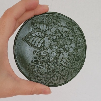 Caixa redonda verde escura com padrão floral em relevo