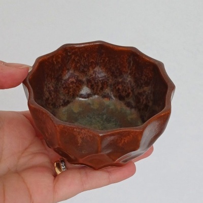 Taça pequena de cerâmica castanha com borda ondulada e interior verde