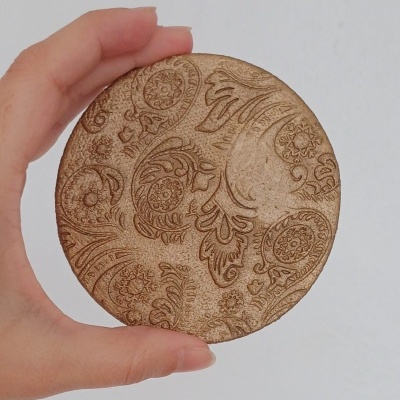Disco redondo castanho com padrão decorativo gravado