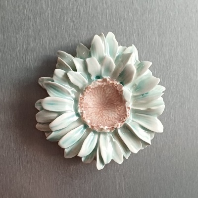 Flor decorativa em cerâmica com pétalas brancas e verdes e centro rosa.