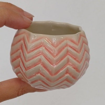 Pequeno vaso cerâmico branco e rosa com padrão ondulado em relevo