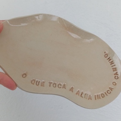 Placa decorativa de cerâmica bege com texto em relevo