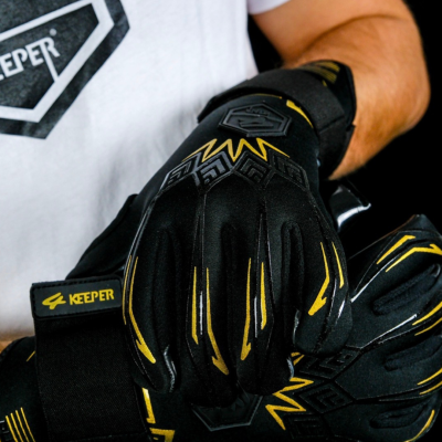 Par de luvas desportivas pretas com detalhes amarelos e fecho ajustável, usadas por uma pessoa com t-shirt branca