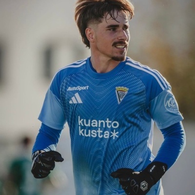 Homem com camisola de futebol azul com logótipos e luvas negras