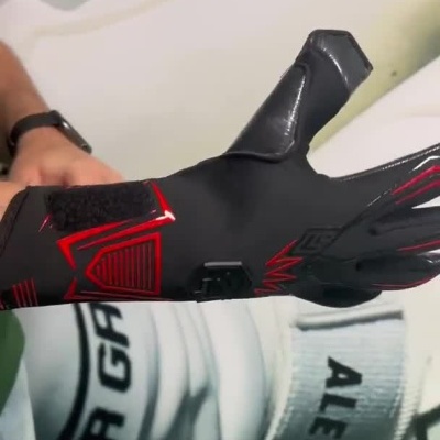 Homem a calçar luva preta com detalhes vermelhos e ajustar tira no pulso