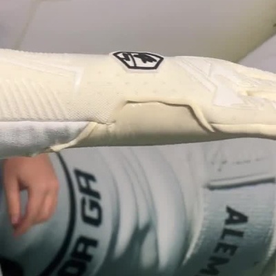 Pessoa a colocar uma luva branca de guarda-redes com logótipo S1 e tira de velcro no pulso