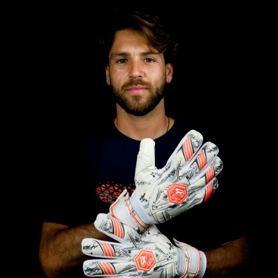 Homem com luvas de guarda-redes brancas com detalhes laranja e cinzentos