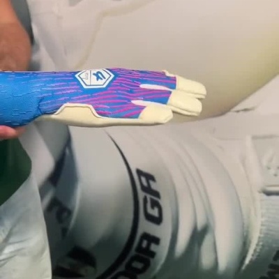 Pessoa a vestir luva desportiva azul com detalhes cor de rosa e ajustar fita branca no pulso