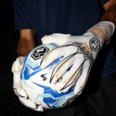 Pessoa a segurar bola de futebol com luvas de guarda-redes brancas com detalhes pretos e laranja.