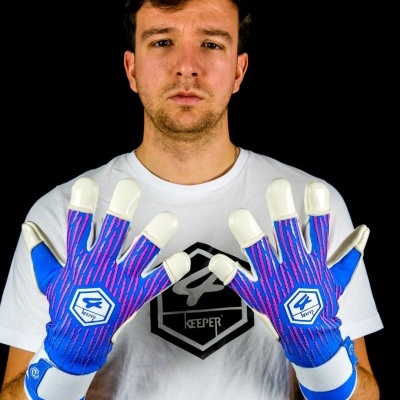 Homem de frente com luvas de guarda-redes azuis e rosa e t-shirt branca com logotipo