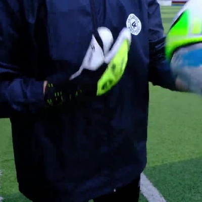 Jogador a calçar luvas de guarda-redes e a segurar bola de futebol colorida