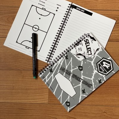 Dois cadernos em espiral e uma caneta sobre mesa de madeira