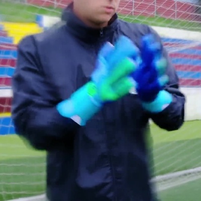 Guarda-redes a calçar luvas e preparar defesa no campo de futebol