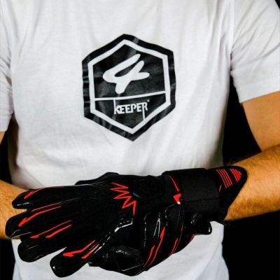 Pessoa com t-shirt branca com logótipo 4 KEEPER e luvas negras com detalhes vermelhos