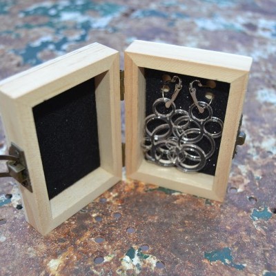 Brincos de argolas prateadas em caixa de madeira com interior preto