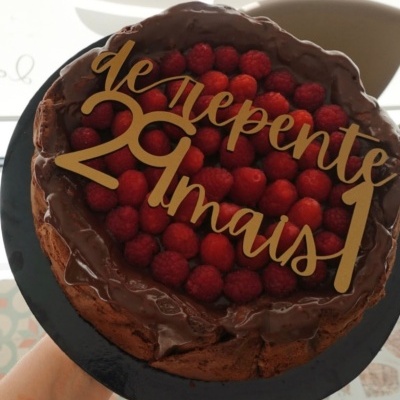 Bolo de chocolate com framboesas e placa decorativa dourada com texto