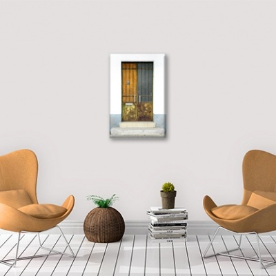 Sala com duas cadeiras cor de ferrugem, planta em cesto, pilha de livros e quadro de porta amarela