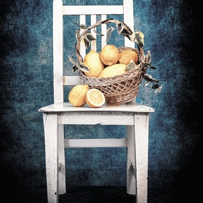 Cadeira branca rústica com cesta de limões e folhas secas