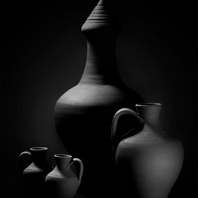 Quatro jarros em cerâmica preta sobre fundo escuro