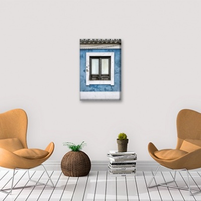 Sala com dois cadeirões laranja, cesto, plantas, livros e fotografia de uma janela azul na parede branca