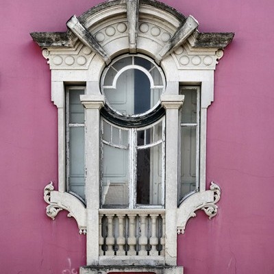 Janela ornamentada em pedra numa parede rosa