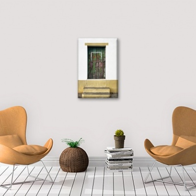 Duas cadeiras lounge caramelo com planta, livros e quadro de porta verde na parede