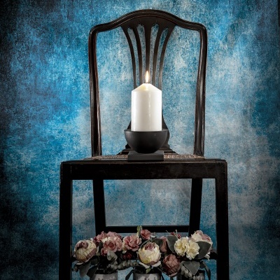 Cadeira de madeira escura com vela acesa e vasos de flores