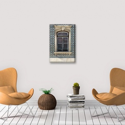 Duas cadeiras laranja com vaso redondo e pilha de livros sob quadro de janela antiga