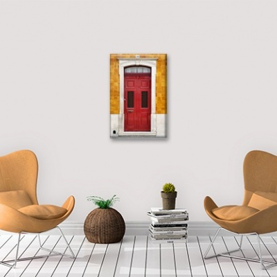 sala com cadeiras castanhas, mesa redonda com planta, livros e quadro de porta vermelha