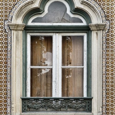 Janela antiga de madeira com vidro em parede de azulejos castanhos.