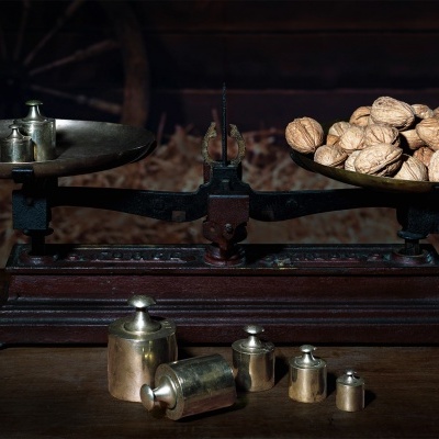 Balança antiga com nozes e pesos metálicos sobre mesa de madeira