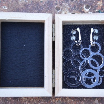 Brincos prateados em caixa de madeira com interior em veludo preto