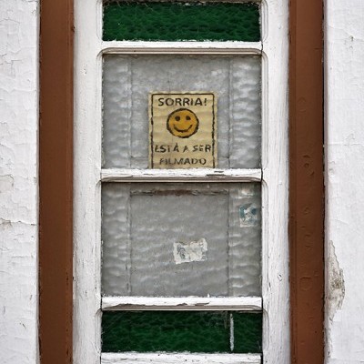 Janela com vidro texturizado e papel com aviso de filmagem e smiley