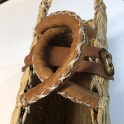 Cesto de verga com alça de couro castanho e fivela metálica dourada