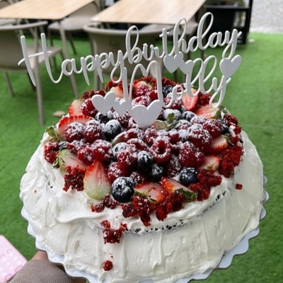 Bolo de aniversário com chantilly e frutas vermelhas, decoração com mensagem 'Happy birthday Molly'