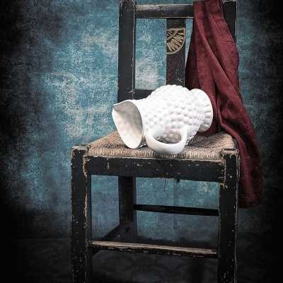 Cadeira antiga de madeira preta com jarro branco e tecido vermelho