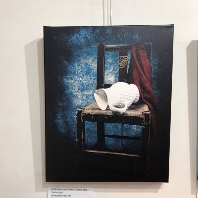 Quadro com cadeira de madeira, cerâmica branca e tecido vermelho sobre fundo azul escuro