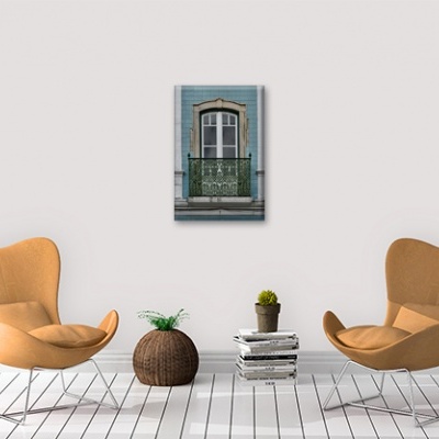 Duas cadeiras bege, puff em fibra natural, livros e planta com tela de janela azul na parede