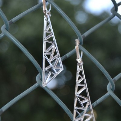 Brincos triangulares prateados pendurados num arame