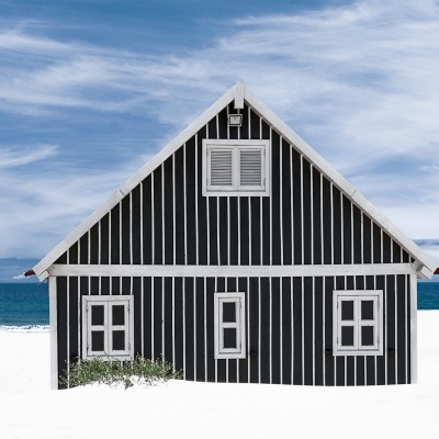 Casa de praia preta com riscas brancas na praia com mar e céu azul