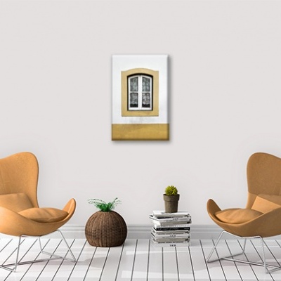 Sala minimalista com duas cadeiras caramelo, planta em mesa de vime, livros e quadro de janela na parede branca.