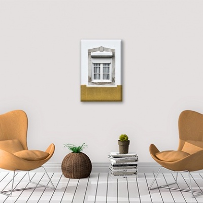 Sala com duas cadeiras castanho claro, cesto de fibra, livros e quadro de janela branca na parede