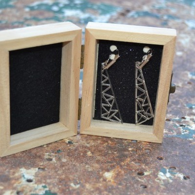 Brincos triangulares metálicos prateados em caixa de madeira pequena com interior preto