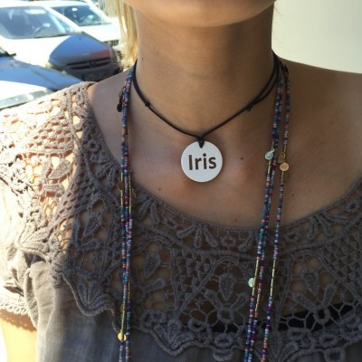 Colar com pendente branco escrito 'Iris' e blusa cinzenta bordada