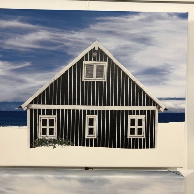 Tela pintada de uma casa preta com riscas brancas e mar ao fundo