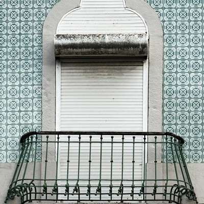 Janela com persiana branca fechada e varanda com grade metálica verde