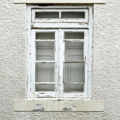 Janela de madeira branca velha com vidro em parede clara texturada