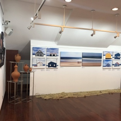 Galeria com quadros de paisagens marítimas coloridas e parede branca